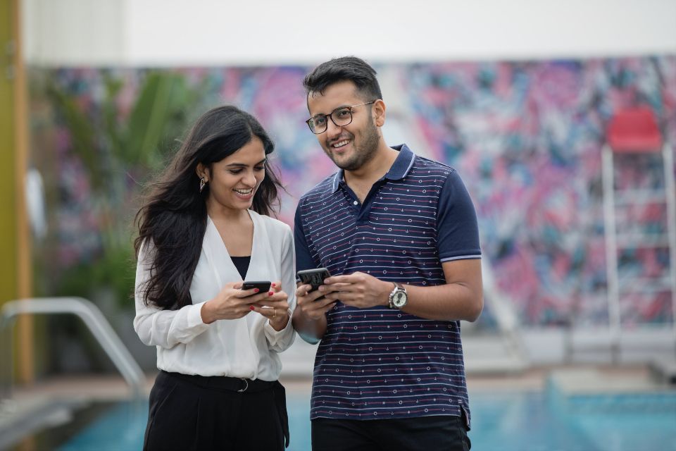 Two colleagues smiling while looking at their phones together