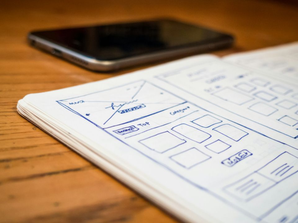 Hand-drawn website wireframe sketches in a notebook on a wooden desk